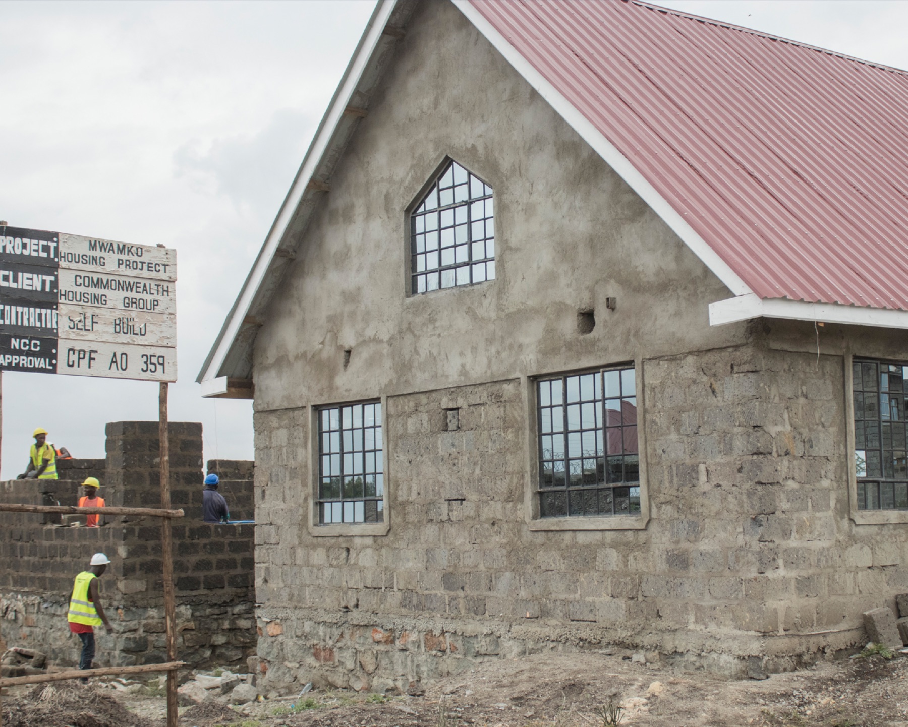 A completed MWAMKO family home at Kamulu: a stone-built house with a red pitched roof and a covered porch.