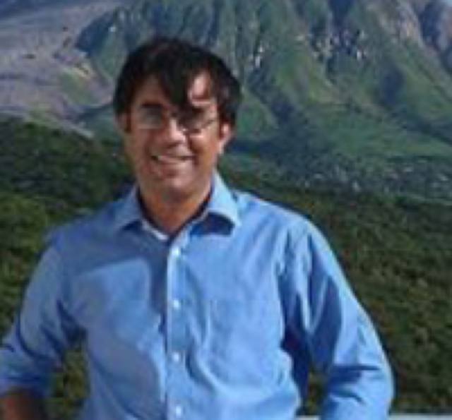 Ripin Kalra in a blue shirt with green mountains behind.