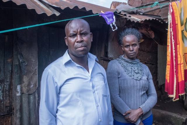 Joseph and his wife standing in front of their corrugated-iron home in Korogocho.