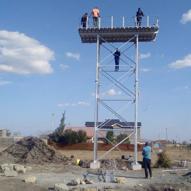 Workers on top of the newly erected steel water tower at the Kamulu site.