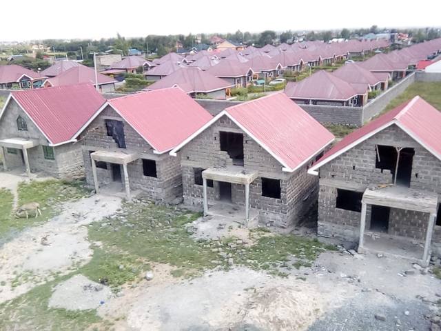Aerial view of rows of grey stone houses with red roofs at the project site.